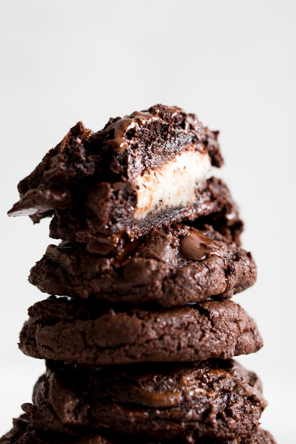 A close up image of a stack of chocolate peppermint patty cookies with the top cookie cut in half to show the inside patty.