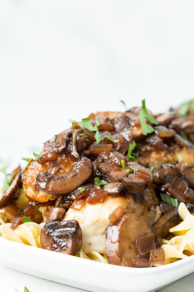 image of a white platter with mushroom chicken bourguignon and fresh parsley