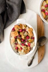 Overhead shot of stuffing in white casserole dish on a white and wood backdrop